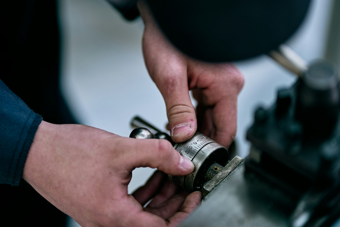 Hands manipulate a metal device on a table.